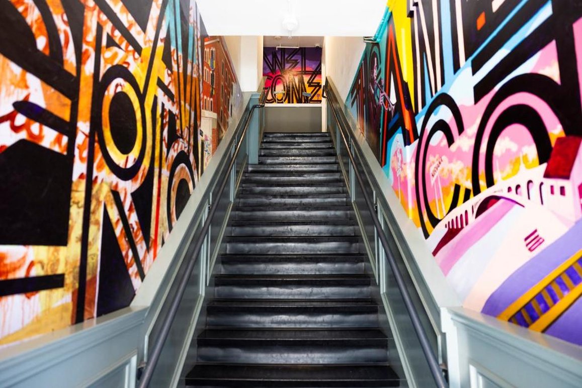 A staircase with colorful graffiti on the walls and a metal railing