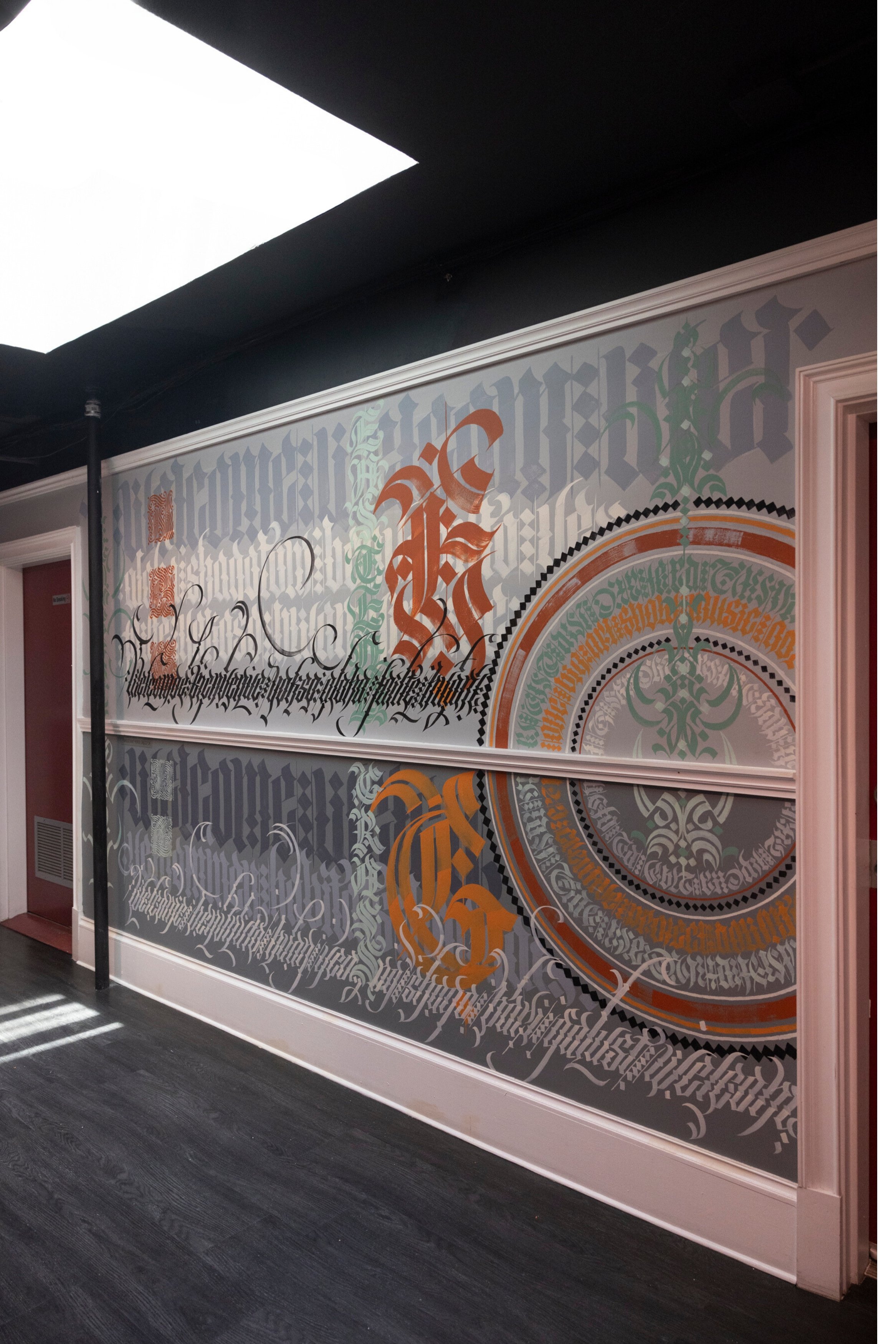 A large wall with colorful art and a skylight above