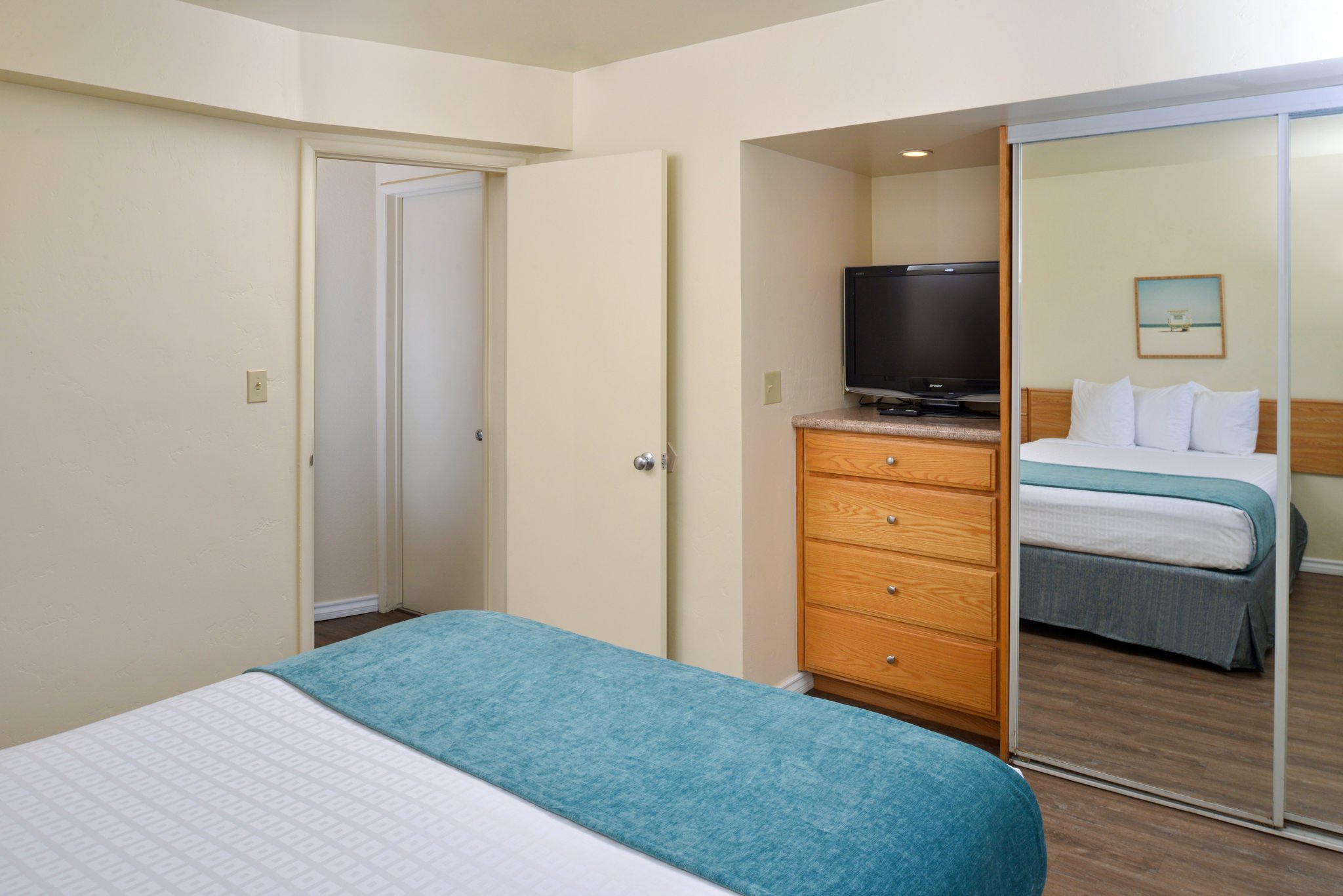 A hotel room with a bed, dresser, and TV.