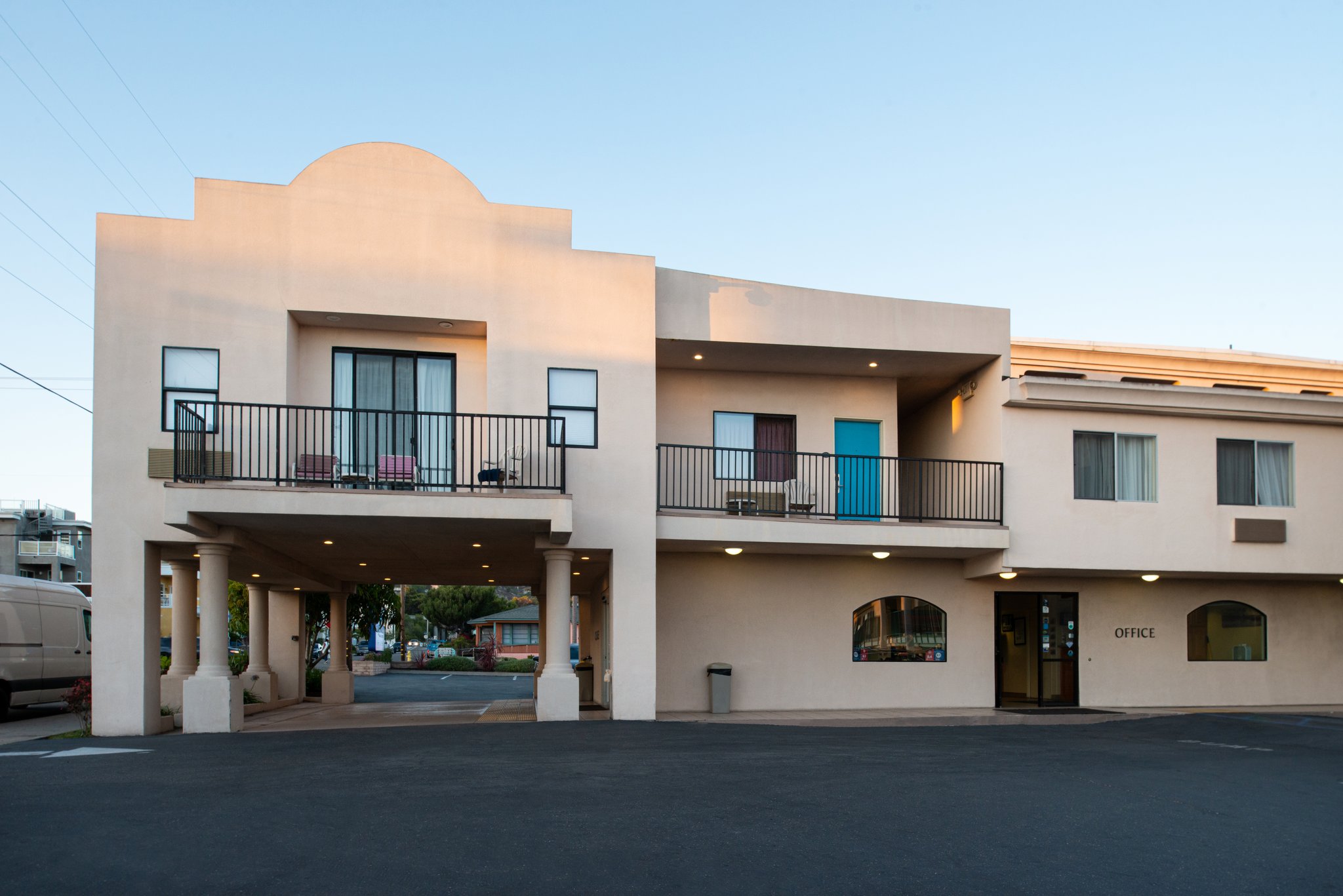 A two-story beige stucco building with balconies and a parking lot.